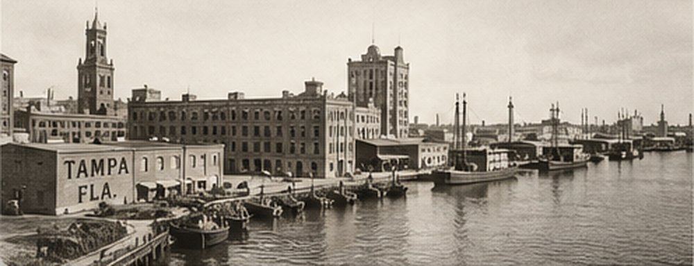 A historic sepia photograph of the Tampa waterfront and warehouses.